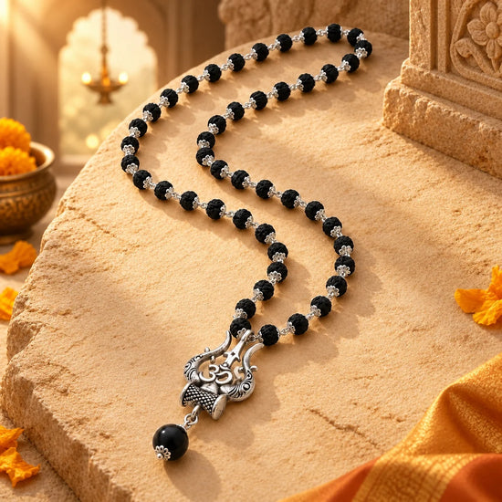 Original Karungali Mala with Silver Plated Om Trishul Pendant on warm sandstone